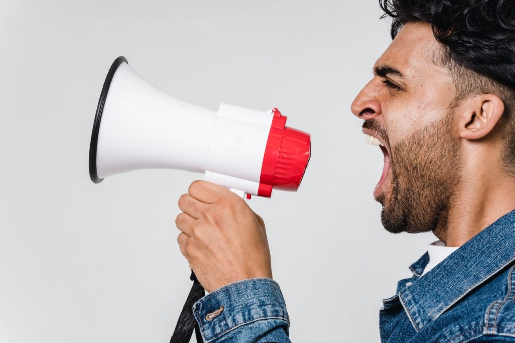 A man screaming into a megaphone. The megaphone illustrate word of mouth marketing. One of the ways SEO can benefit your small business.
